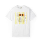 A white short-sleeve crewneck t-shirt featuring a graphic print on the front with yellow vertical stripes, the text 'COOL MOM'S CLUB' in black outline letters, and two sunflower graphics replacing the 'O's.