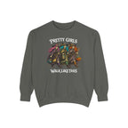 A dark gray crewneck sweatshirt featuring a graphic of four stylized witches riding a pumpkin cart, with the text 'PRETTY GIRLS WALK LIKE THIS' printed in white above and below the illustration.