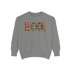 A gray crewneck sweatshirt featuring the word 'BOO!' in a plaid pattern across the chest, with an exclamation mark. The plaid pattern contains orange, green, and brown tones.