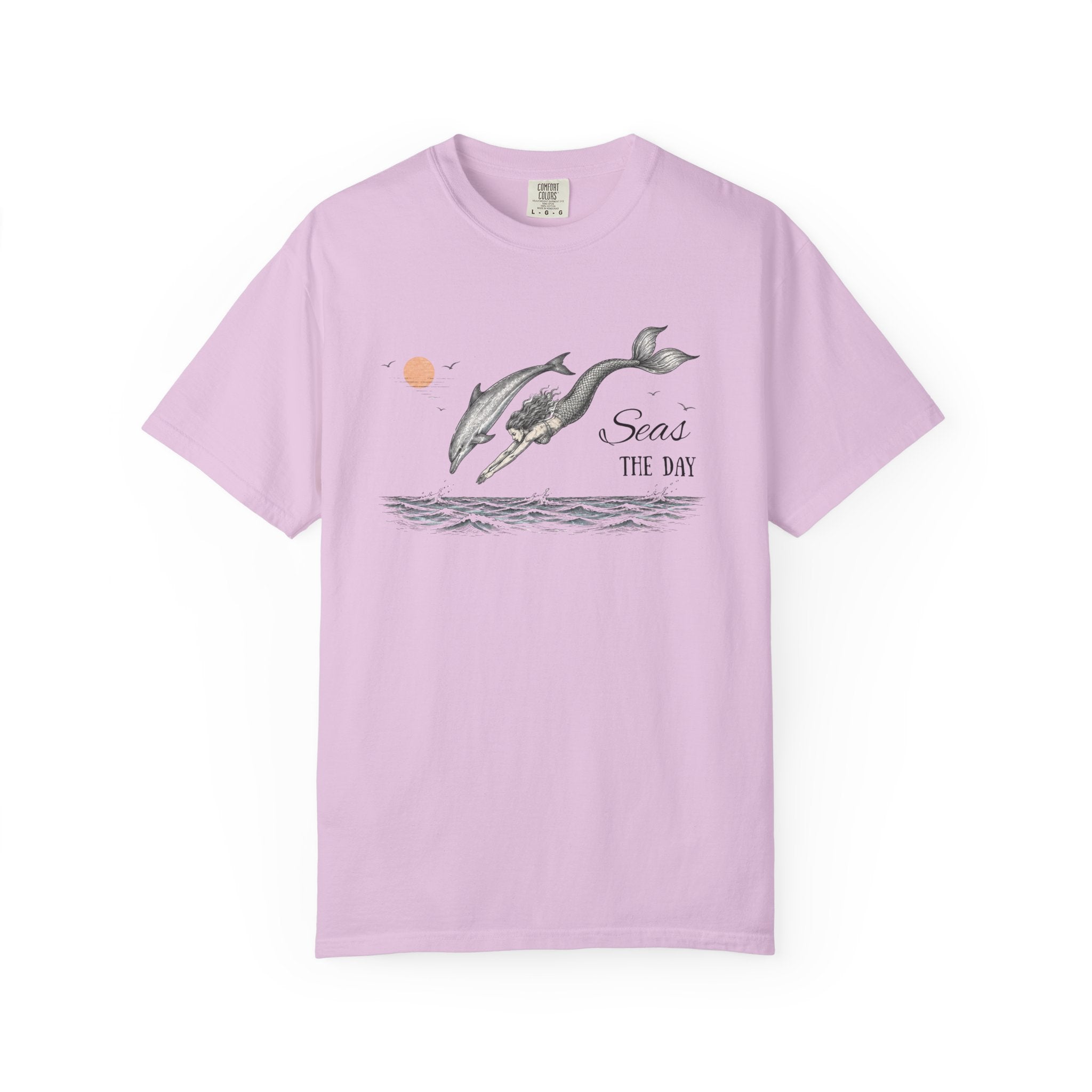 A light purple short-sleeve crewneck t-shirt featuring a graphic print of two dolphins jumping over water with the text 'Seas THE DAY' and a small orange sun.
