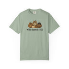 A sage green short-sleeve t-shirt with a graphic of pumpkins and the text 'WILD ABOUT FALL' printed on the chest, displayed against a plain white background.