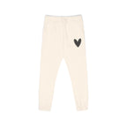 Off-white fleece jogger pants with a small black heart graphic on the upper left leg, featuring an elastic waistband with a drawstring and elastic cuffs.