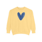 A pale yellow crewneck sweatshirt featuring a textured blue heart graphic printed on the center chest, displayed against a solid white background.