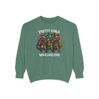 A sage green crewneck sweatshirt featuring a graphic of four witches riding on a pumpkin cart, with the text 'PRETTY GIRLS WALK LIKE THIS' printed in white around the illustration.
