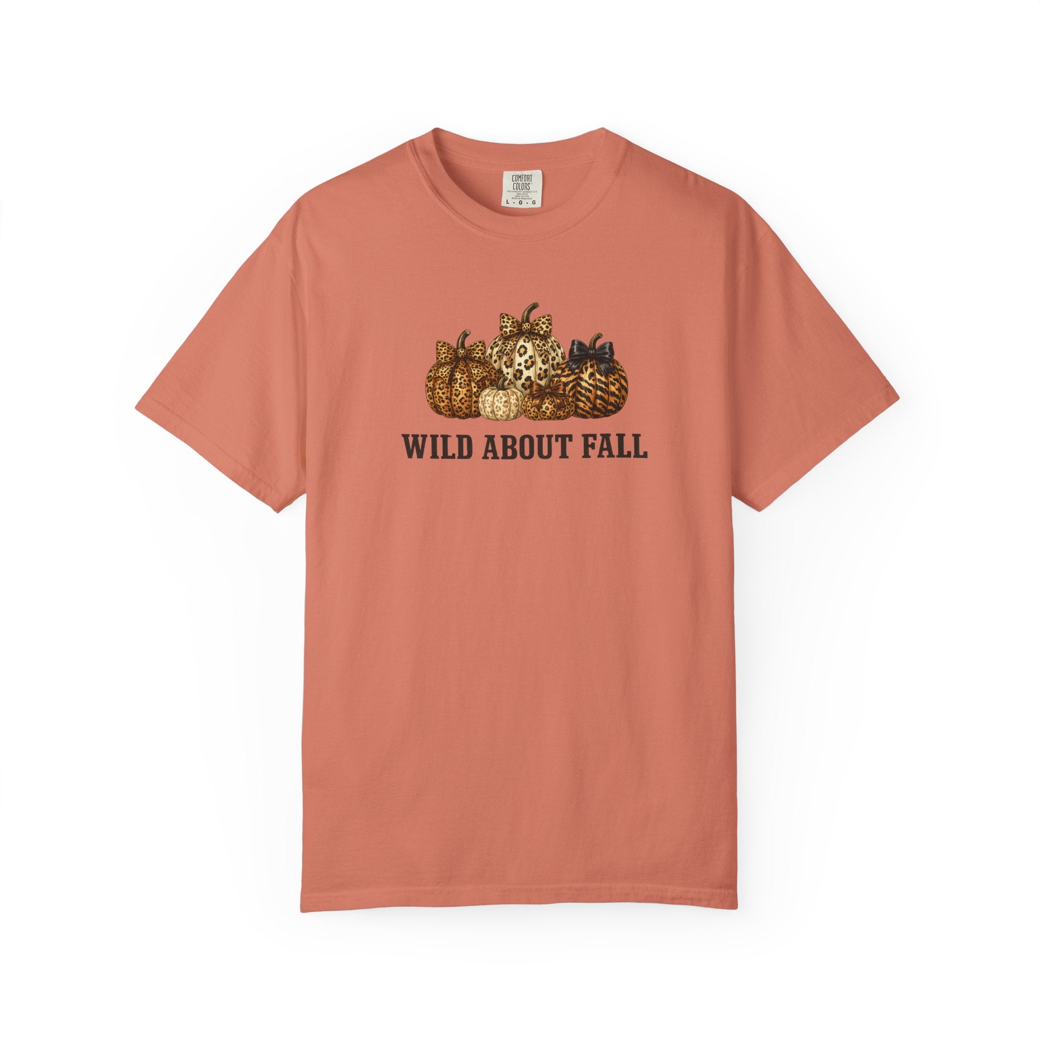 A short-sleeve crewneck t-shirt in a muted terracotta or salmon pink color, featuring a graphic of pumpkins and the text 'WILD ABOUT FALL' printed on the chest.