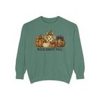 A sage green crewneck sweatshirt featuring a graphic of patterned pumpkins and the text 'WILD ABOUT FALL' printed on the chest, displayed against a solid white background.