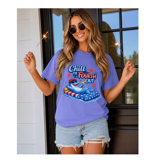Woman wearing a purple 'Chill the Fourth Out' t-shirt with a graphic of a shark on a beach.
