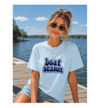 Woman wearing a 'boat season' t-shirt by a lake