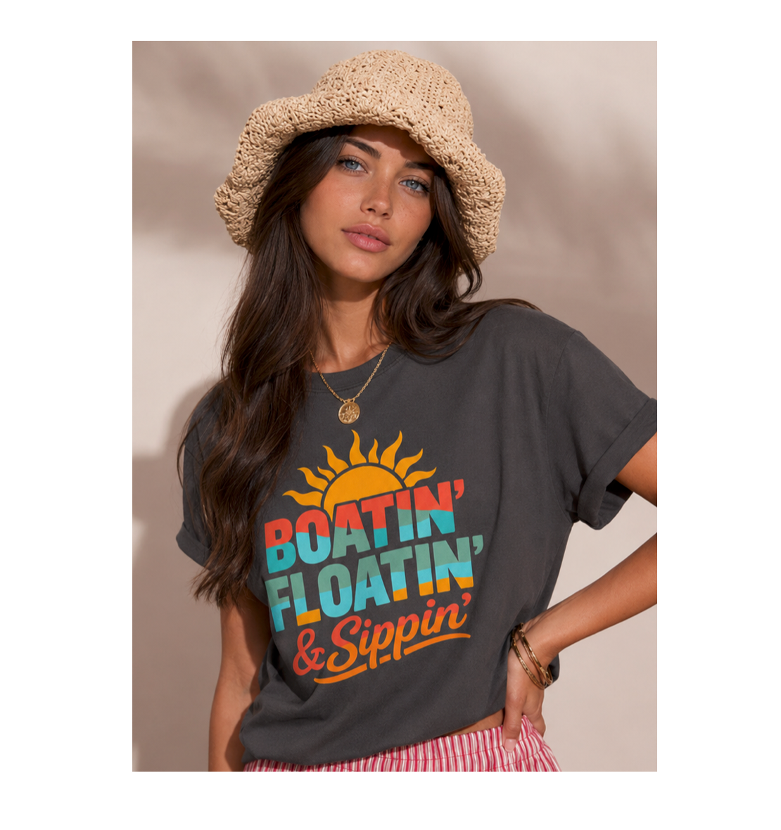 Woman wearing a gray t-shirt with colorful text and a sun graphic, standing against a plain background.