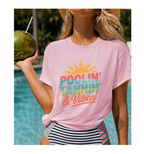 Woman wearing a pink t-shirt with 'Poolin' Tanning & Vibin' text by a pool.
