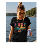 Woman wearing a black t-shirt with 'Lake Life' design by a lake.