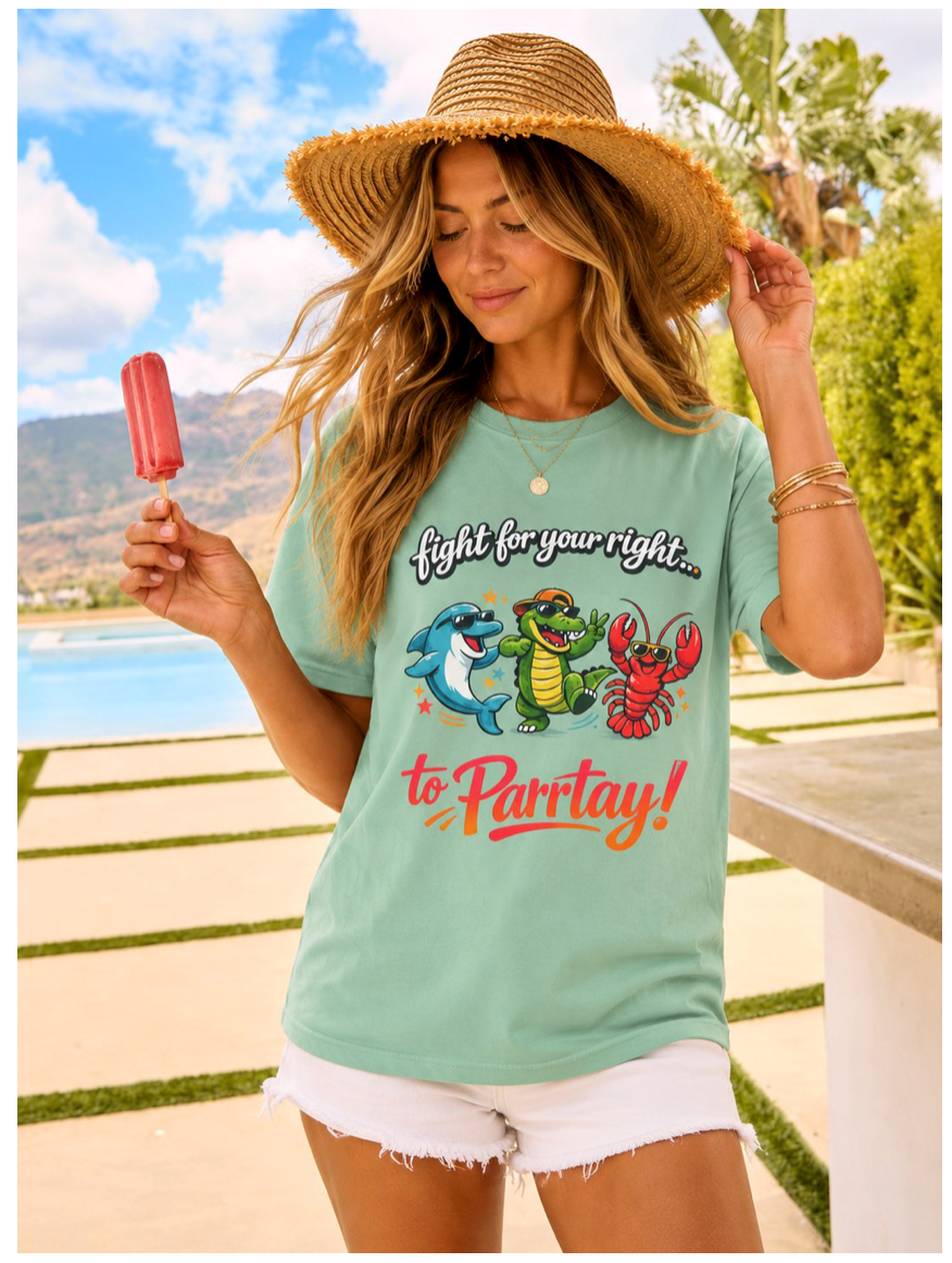 Woman wearing a light green t-shirt with cartoon characters and text, holding a popsicle outdoors.