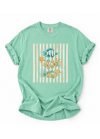 Light green t-shirt with a fish and shell design on a white background