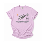 A light purple short-sleeve t-shirt with a graphic of two whales jumping out of the water, a small orange sun, and the text 'Seas THE DAY'.