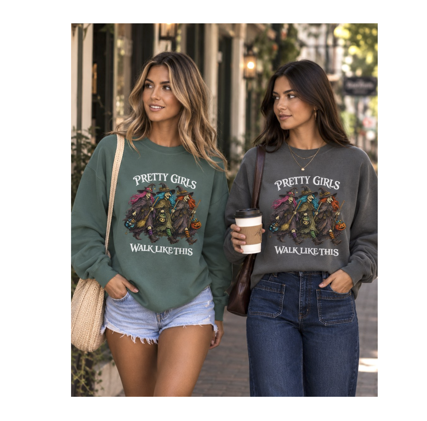 Two women walking outdoors on a city street wearing matching graphic sweatshirts. The sweatshirt on the left is sage green with a colorful illustration and the text 'PRETTY GIRLS WALK LIKE THIS,' and the sweatshirt on the right is charcoal gray with the same graphic and text.